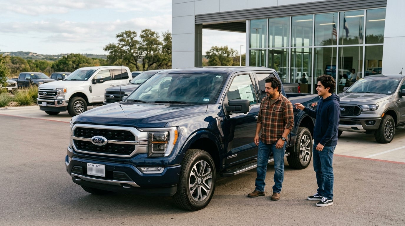 A man and a young man standing next to a dark blue Ford F-150 pickup truck at a car dealership. (Representative image for illustration purposes only. Actual vehicle may vary based on trim and configuration.)