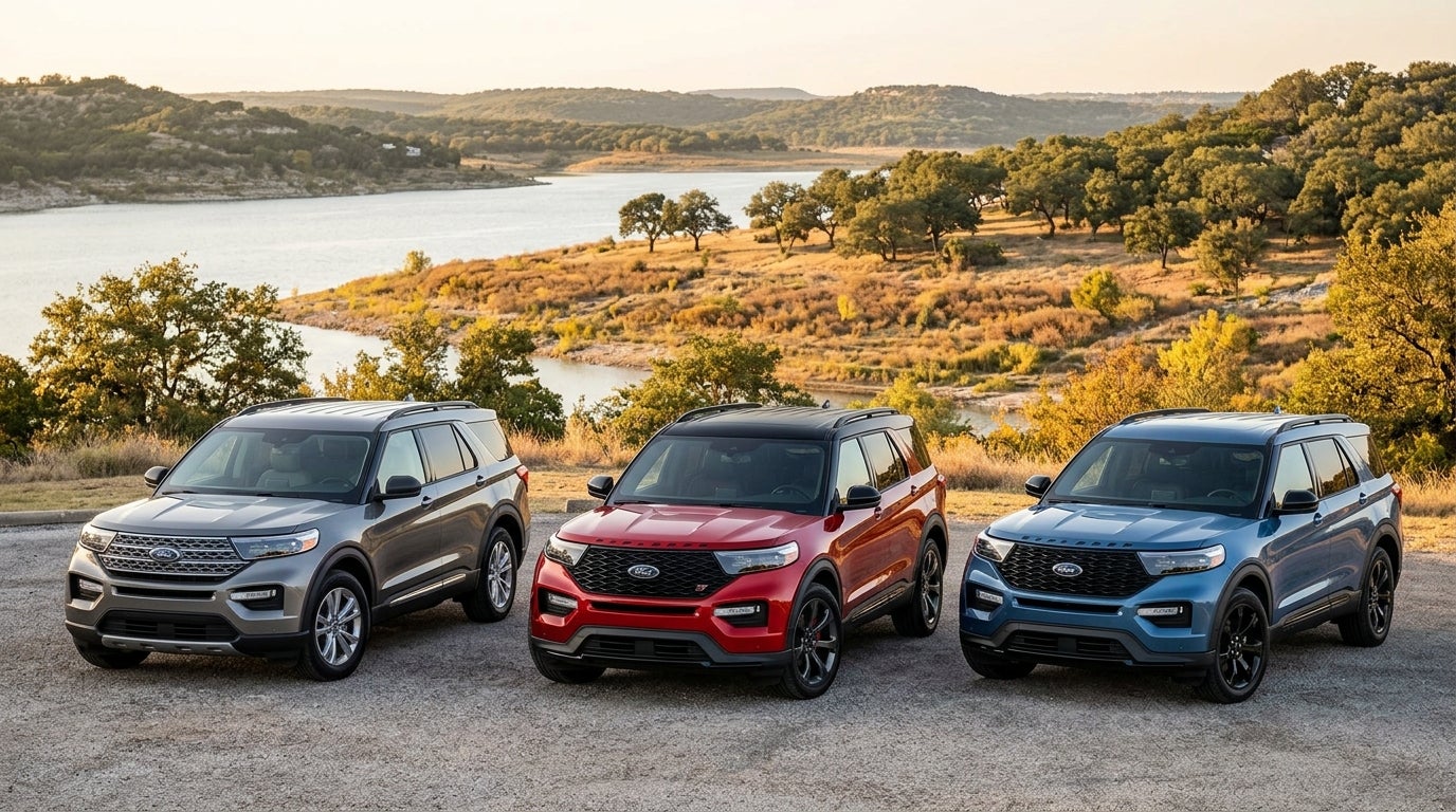 Three Ford Explorer SUVs in silver, red, and blue parked on gravel overlooking a scenic lake landscape at sunset. (Representative image for illustration purposes only. Actual vehicle may vary based on trim and configuration.)